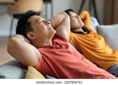 Relaxed Korean Lovers Resting Together At Home, Happy Middle Aged Asian Man And Pretty Young Woman Reclining On Couch With Closed Eyes And Hands Behind Their Heads, Side View