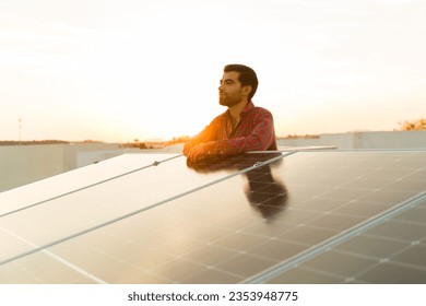 Relaxed latin man and home owner at the rooftop looking happy about using solar panels and clean sustainable energy - Powered by Shutterstock