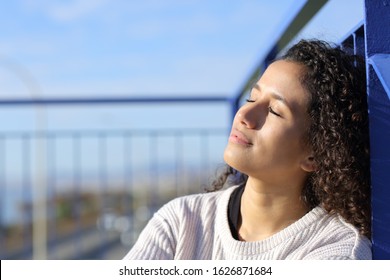 Relaxed latina girl sitting on stairs leaning in a railing heating in a sunny day
