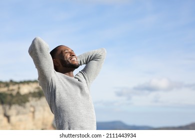 Relaxed man with black skin breathing fresh air with hands on head in the mountain - Shutterstock ID 2111443934
