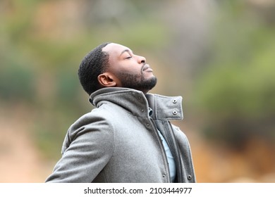 Relaxed man with black skin in winter breathing fresh air outdoors