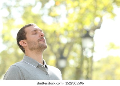 Relaxed Man Breathing Deeply Fresh Air Standing Outside In A Park With Trees In The Background