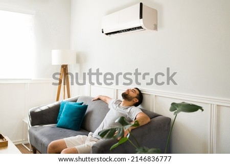 Relaxed man chilling and resting on the sofa while enjoying the new ac unit during a hot summer