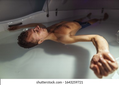 Relaxed Man Is Floating In A Sensory Deprivation Tank. He Is Very Relaxed. Welness And Spa Concept.