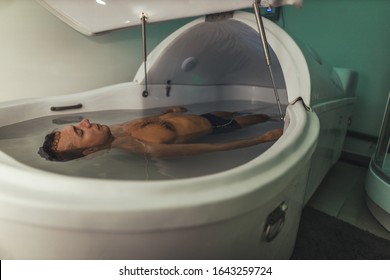 Relaxed Man Is Floating In A Sensory Deprivation Tank. He Is Very Relaxed. Welness And Spa Concept.