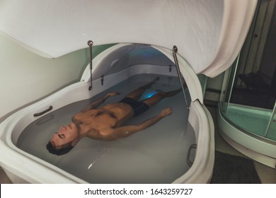 Relaxed Man Is Floating In A Sensory Deprivation Tank. He Is Very Relaxed. Welness And Spa Concept.