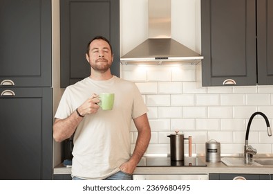 Relaxed man leaning on his kitchen counter while he is enjoying a coffee. - Powered by Shutterstock