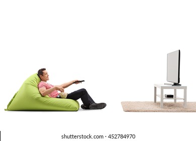 Relaxed Man Sitting On A Comfortable Green Beanbag And Watching TV Isolated On White Background