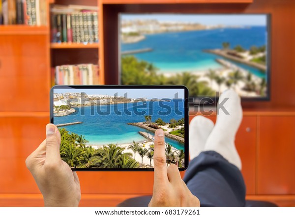 relaxed man with\
smart tv and tablet connected to a tv and envisioning photos in\
networking tv and telephone image from a photo of a beach canary\
island is from my\
portfolio)