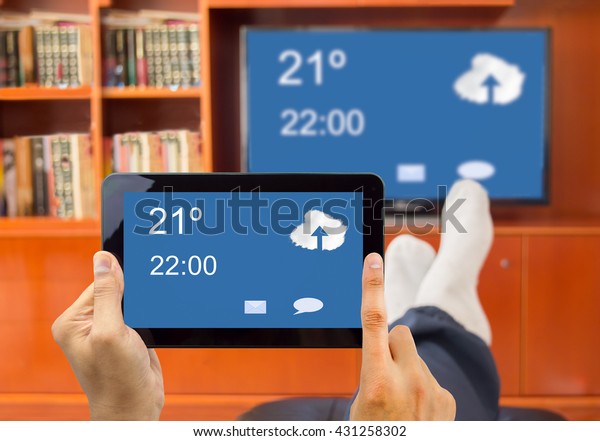 relaxed man with tablet connected to a tv\
through wireless connection in\
networking