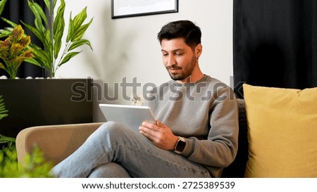 Relaxed man using tablet computer on sofa in modern living room