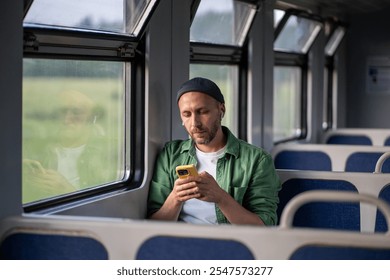 Relaxed man wearing wireless earphones, using smartphone and surfing Internet, social media in train car.  - Powered by Shutterstock