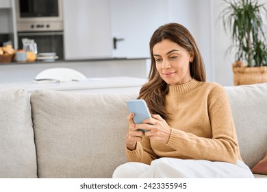 Relaxed middle aged older woman using smartphone sitting on couch at home. Happy mature lady holding cellphone browsing internet, texting messages on mobile cell phone technology on sofa. - Powered by Shutterstock