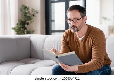 Relaxed pensive middle-aged mature man father husband author freelancer tutor adult student lecturer reading book at home, preparing for exams at university, enjoying novels at leisure time. - Powered by Shutterstock