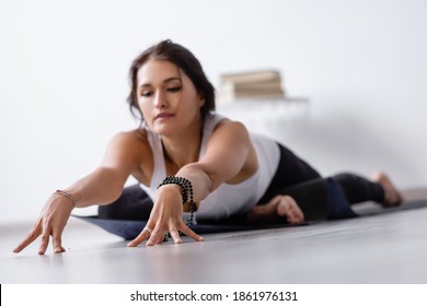 Relaxed positive young woman doing stretching and enjoying body recovery with eyes closed. Concept of improving the health and blood supply to the body. Stretching and Pilates at home