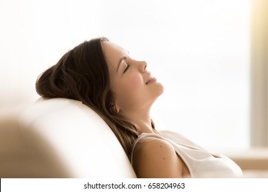 Relaxed pretty young woman lying on comfortable sofa with closed eyes. Satisfied adorable teenager girl resting at home, dozing on soft coach, enjoys leisure. Female dreaming about pleasant future - Shutterstock ID 658204963