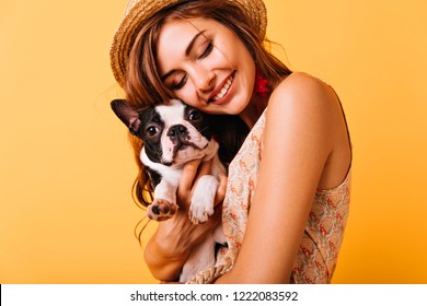 Relaxed Red-haired Girl Embracing Puppy On Yellow Background. Studio Portrait Of White Appealing Woman Chilling With Dog.