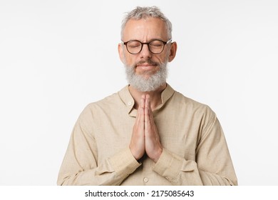 Relaxed resting caucasian mature middle-aged man in beige shirt praying meditating feeling zen-like with eyes closed, doing breathing exercises isolated in white background - Shutterstock ID 2175085643