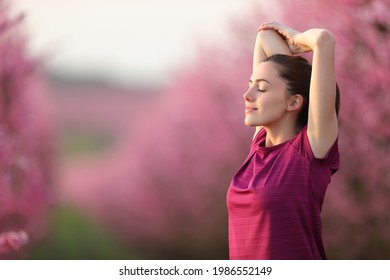Relaxed runner stretching arms after exercise in a pink flowered field - Shutterstock ID 1986552149
