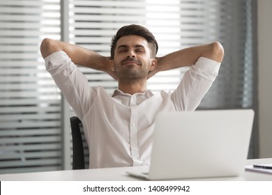 Relaxed satisfied positive calm lazy business man relax take break at work hold hand behind head sit at office desk dream rest from computer stretch feel no stress relief peace of mind at workplace