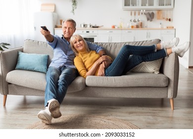 Relaxed Senior Couple Watching Television Together Sitting On Sofa And Pointing Remote Controller Switching Channels Relaxing At Home On Weekend. TV Programming Concept - Powered by Shutterstock