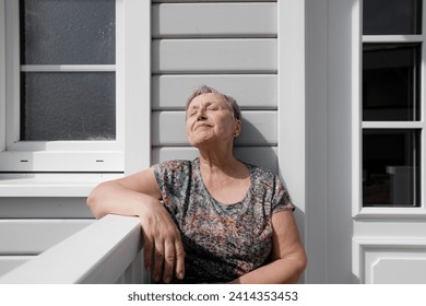 Relaxed senior woman sitting on porch in sunshine - Powered by Shutterstock