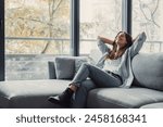 Relaxed serene pretty young woman feel fatigue lounge on comfortable sofa hands behind head rest at home, happy calm lady dream enjoy wellbeing breathing fresh air in cozy home modern living room