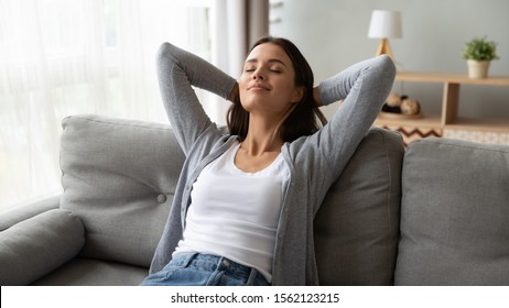 Relaxed serene pretty young woman feel fatigue lounge on comfortable sofa hands behind head rest at home, happy calm lady dream enjoy wellbeing breathing fresh air in cozy home modern living room - Shutterstock ID 1562123215