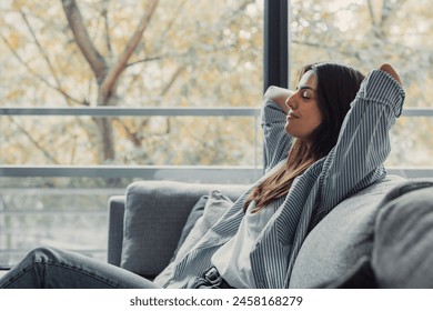 Relaxed serene pretty young woman feel fatigue lounge on comfortable sofa hands behind head rest at home, happy calm lady dream enjoy wellbeing breathing fresh air in cozy home modern living room - Powered by Shutterstock