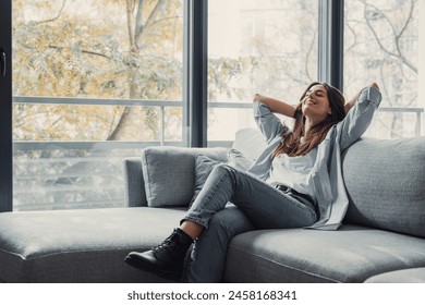 Relaxed serene pretty young woman feel fatigue lounge on comfortable sofa hands behind head rest at home, happy calm lady dream enjoy wellbeing breathing fresh air in cozy home modern living room - Powered by Shutterstock