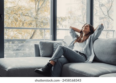 Relaxed serene pretty young woman feel fatigue lounge on comfortable sofa hands behind head rest at home, happy calm lady dream enjoy wellbeing breathing fresh air in cozy home modern living room - Powered by Shutterstock