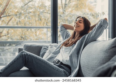 Relaxed serene pretty young woman feel fatigue lounge on comfortable sofa hands behind head rest at home, happy calm lady dream enjoy wellbeing breathing fresh air in cozy home modern living room - Powered by Shutterstock