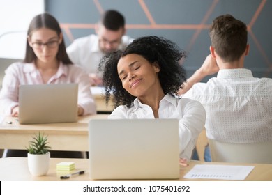 Relaxed smiling african woman enjoying break in coworking, happy millennial black office worker or student feeling no stress free relief at work, afro american intern dreaming of future success 