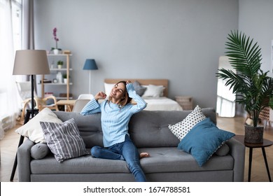 Relaxed smiling woman sitting on sofa at home. Domestic life.