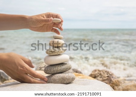 Relaxed spiritually woman hand arrangement pebble tower on cobblestone sea coastline landscape closeup. Yoga female peace of mind relax meditation harmony life balance tranquility equilibrium pyramid