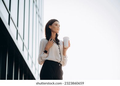 Relaxed stylish businesswoman drinking coffee outside on urban background. - Powered by Shutterstock