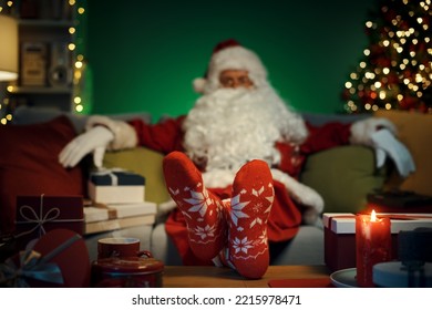 Relaxed tired Santa Claus relaxing on the couch with feet up at home, he is wearing decorated Christmas socks - Powered by Shutterstock