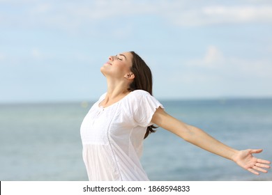 Relaxed woman breathing fresh air and spreading stretching arms on he beach
