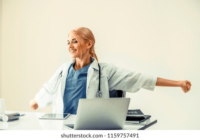 Relaxed Woman Doctor Takes Deep Breath While Working On Medical Report At Office Table. Stress Relief And Control Concept.