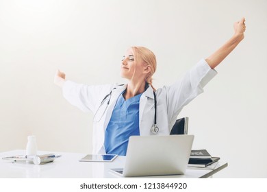 Relaxed Woman Doctor Takes Deep Breath While Working On Medical Report At Office Table. Stress Relief And Control Concept.