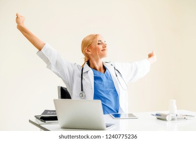 Relaxed Woman Doctor Takes Deep Breath While Working On Medical Report At Office Table. Stress Relief And Control Concept.