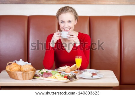 relaxed woman drinking cup of coffee at breakfast table in cafÃ?Â©
