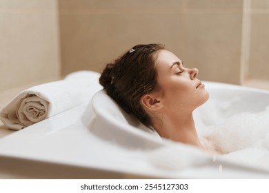 Relaxed woman enjoying a bubble bath, with eyes closed and a serene expression, surrounded by soft towels. Wellness and self-care concept at home spa. - Powered by Shutterstock