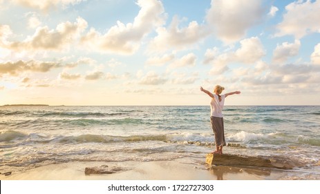 Entspannte Frau genießen Sonne, Freiheit und Leben ein schöner Strand bei Sonnenuntergang. Junge Dame fühlt sich frei, entspannt und glücklich. Konzept von Urlaub, Freiheit, Glück, Genuss und Wohlbefinden.