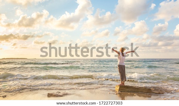Relaxed\
woman enjoying sun, freedom and life an beautiful beach in sunset.\
Young lady feeling free, relaxed and happy. Concept of vacations,\
freedom, happiness, enjoyment and well\
being.