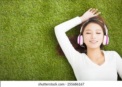 Relaxed Woman Listening To The Music With Headphones Lying On The Grass