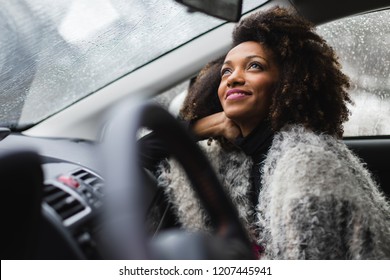 Relaxed Woman Looking The Rain Fall From Inside A Car During Winter Roadtrip.