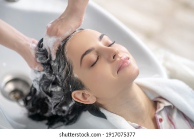 Relaxed. Woman looking relaxed while hair stylist washing her hair - Powered by Shutterstock