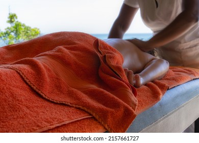 Relaxed Woman Lying Down Getting Massage Therapy In Caribbean Beach Spa With Copy Space