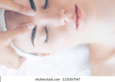 Relaxed woman lying on spa bed for facial and head massage. Concept of beauty and facial treatment.
